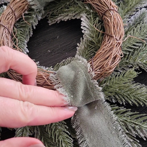 image of ribbon on wreath being glued with straight edge dwelling envy diy dupe of studio mcgee wreath