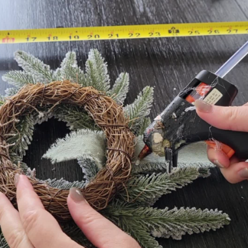 image of gluing ribbon on the underside of wreath for dwelling envy's diy studio mcgee wreath dupe