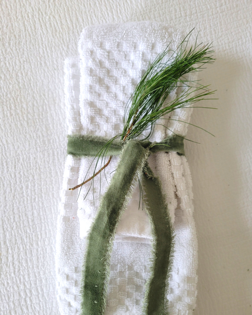 image of matching guest towels tied with green velvet ribbon with a sprig of pine for decoration - dwelling-envy-interiors